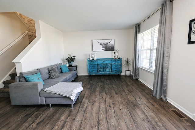 living room with visible vents, baseboards, wood finished floors, and stairway