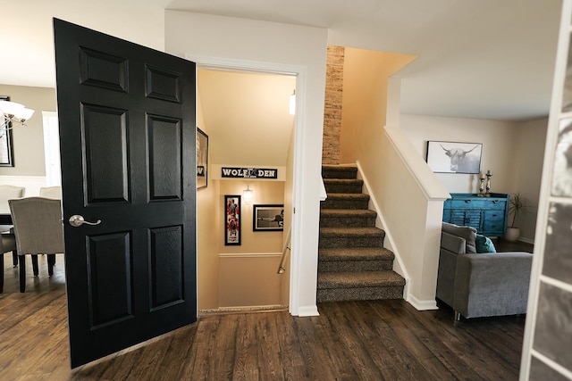 staircase featuring baseboards, a notable chandelier, and wood finished floors