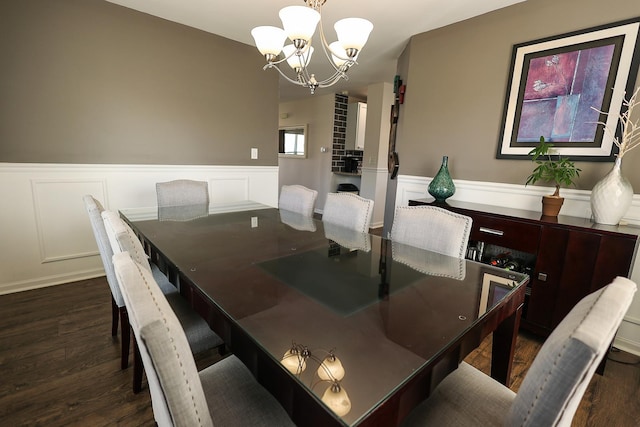 dining area with a wainscoted wall, a decorative wall, dark wood finished floors, and a chandelier