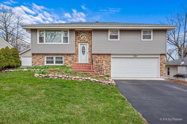 bi-level home with brick siding, a front lawn, a garage, and aphalt driveway