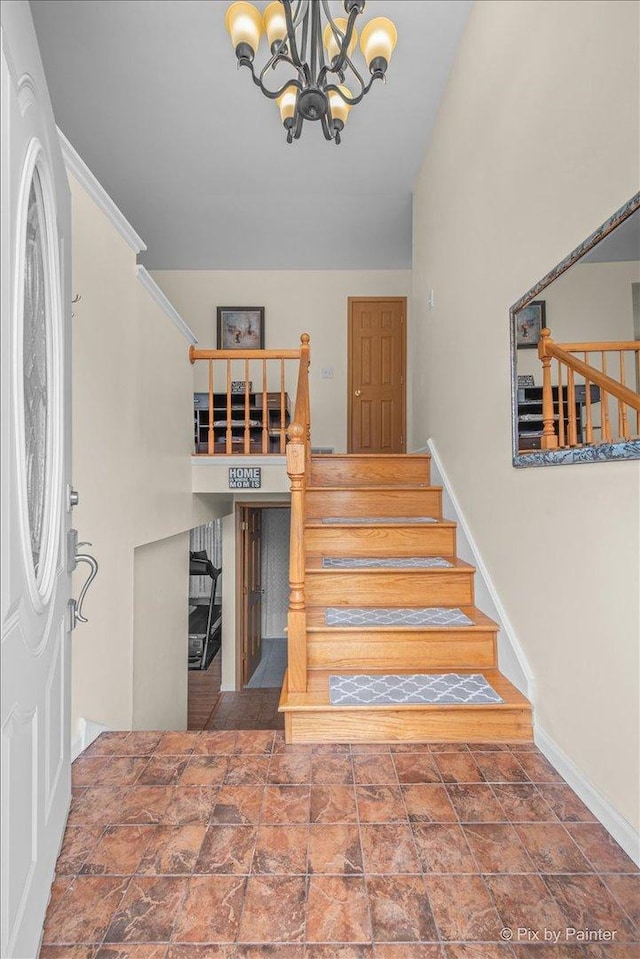foyer entrance with a chandelier, stairs, and baseboards