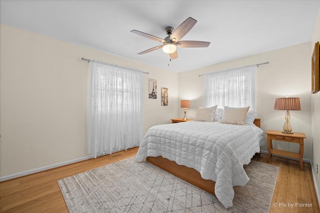 bedroom featuring visible vents, baseboards, a ceiling fan, and wood finished floors