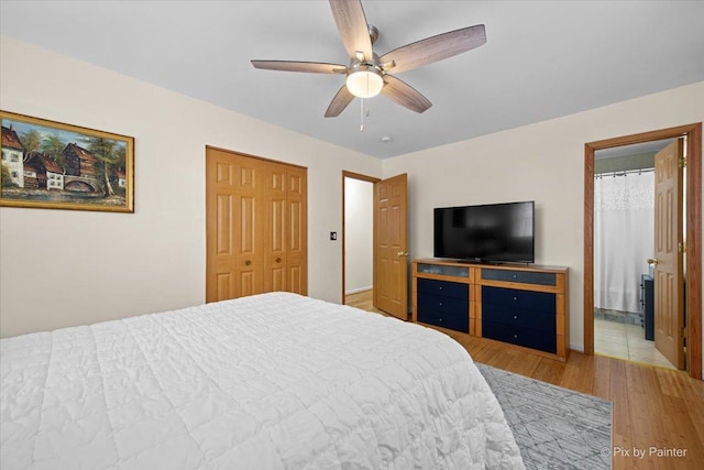 bedroom with light wood-style flooring, baseboards, a ceiling fan, and ensuite bath