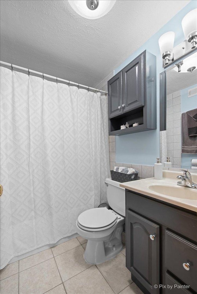 full bathroom with vanity, curtained shower, tile patterned floors, a textured ceiling, and toilet