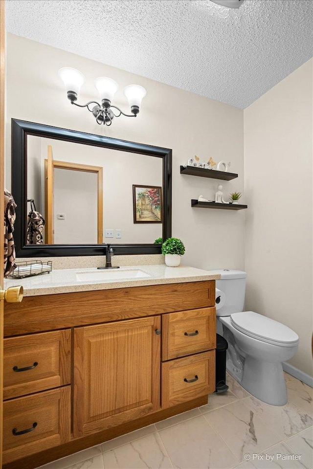 bathroom featuring vanity, marble finish floor, a textured ceiling, and toilet
