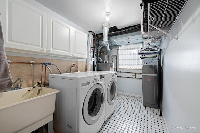 clothes washing area with baseboards, washing machine and clothes dryer, a sink, and cabinet space