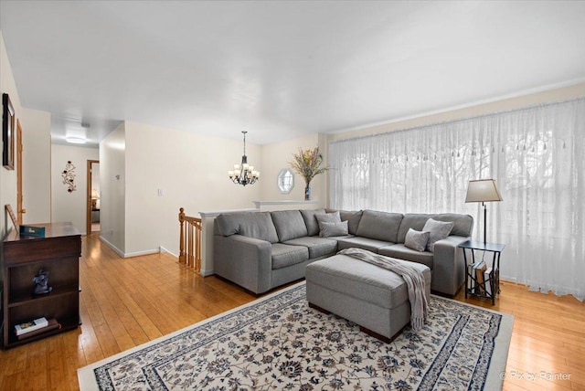 living room featuring wood-type flooring, a notable chandelier, and baseboards
