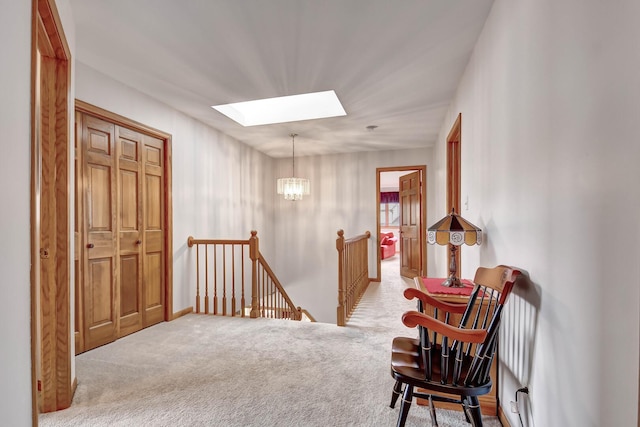 living area with an inviting chandelier, baseboards, an upstairs landing, carpet, and a skylight