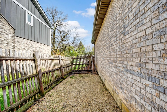 view of property exterior featuring brick siding, board and batten siding, and fence