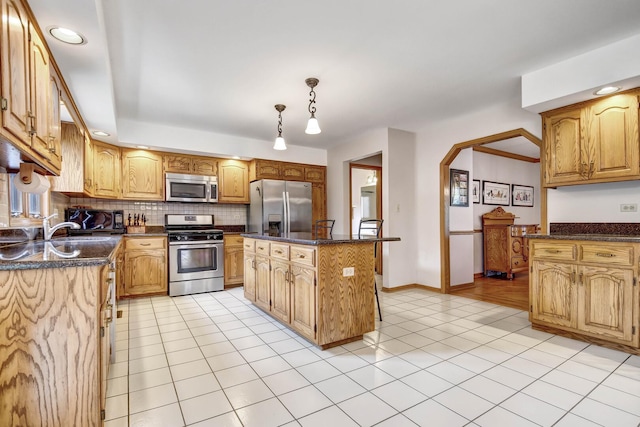 kitchen featuring dark stone countertops, appliances with stainless steel finishes, backsplash, and light tile patterned flooring