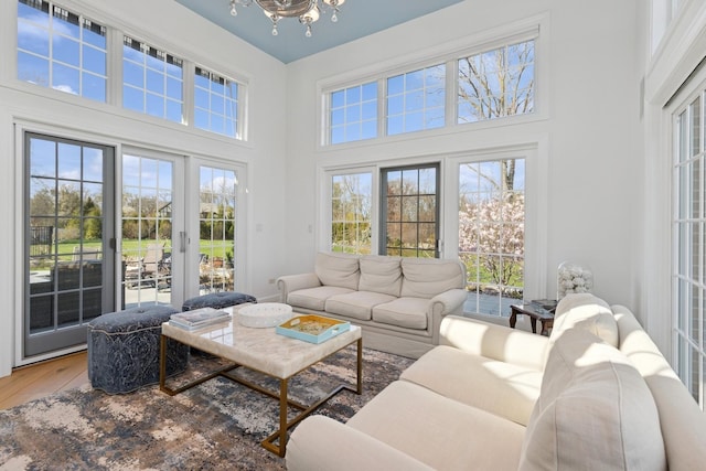 living area featuring a high ceiling, a notable chandelier, and wood finished floors