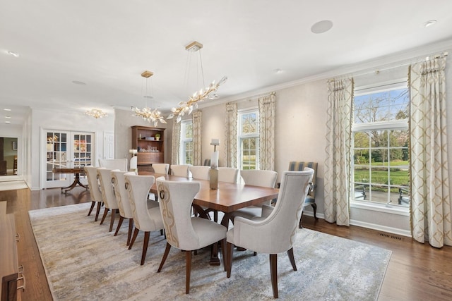 dining room featuring a chandelier, visible vents, wood finished floors, and baseboards