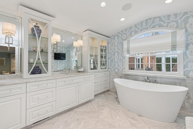 full bath with lofted ceiling, visible vents, and wallpapered walls