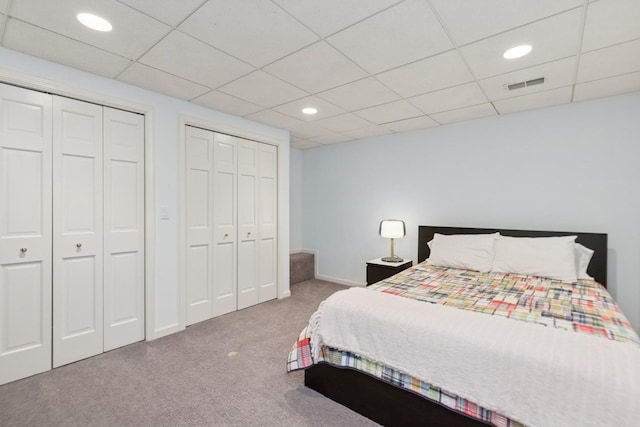 bedroom featuring recessed lighting, carpet floors, visible vents, a drop ceiling, and multiple closets