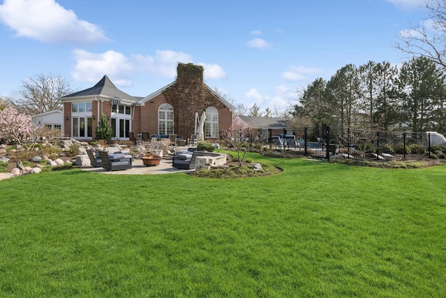 rear view of property featuring brick siding, fence, a yard, and a patio area