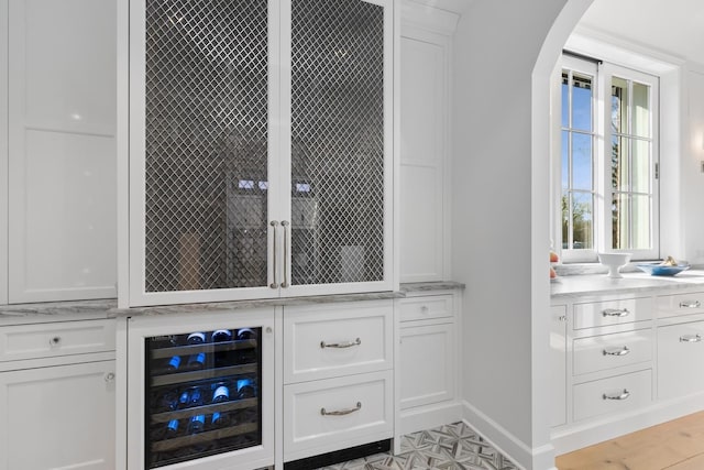bar with baseboards, beverage cooler, and arched walkways