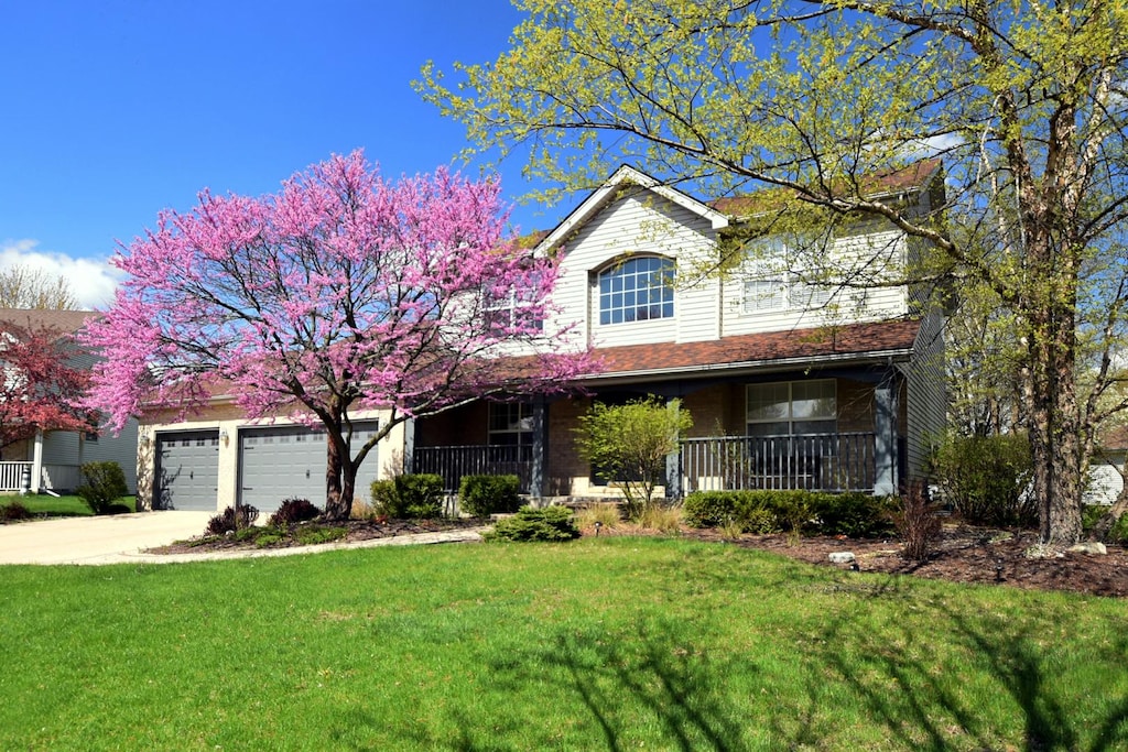 view of front of house with a porch, a garage, a front lawn, and concrete driveway