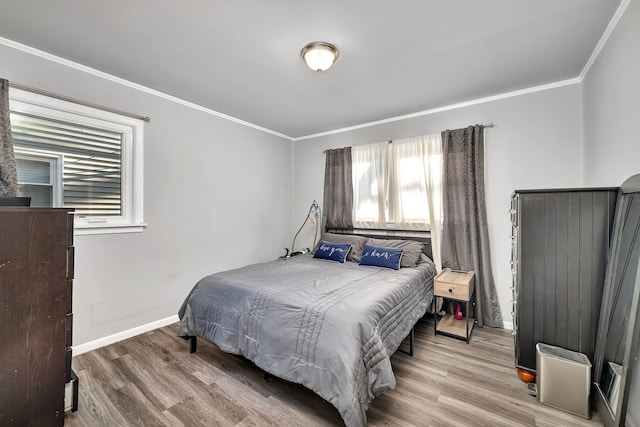 bedroom featuring baseboards, wood finished floors, and crown molding