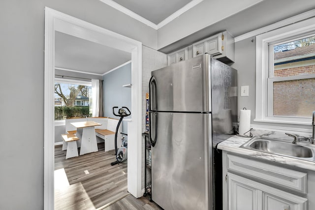 interior space featuring light countertops, a sink, freestanding refrigerator, crown molding, and light wood-style flooring