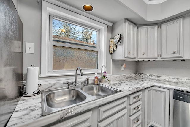 kitchen featuring stainless steel dishwasher, light stone counters, a sink, decorative backsplash, and white cabinets