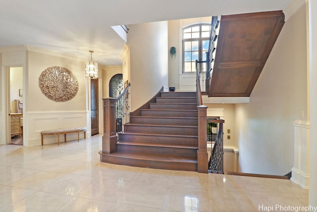 staircase with a decorative wall, tile patterned flooring, and a wainscoted wall