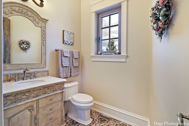 half bathroom featuring vanity, baseboards, and toilet