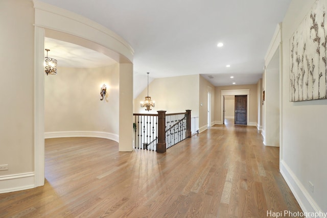 spare room featuring a chandelier, wood finished floors, baseboards, and recessed lighting