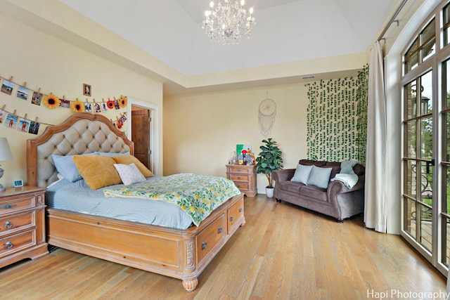 bedroom featuring access to exterior, light wood-style floors, a high ceiling, and an inviting chandelier