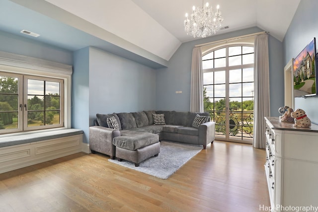 living room with a chandelier, light wood-style floors, visible vents, and vaulted ceiling