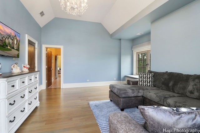 living room with light wood-style floors, visible vents, a chandelier, lofted ceiling, and baseboards