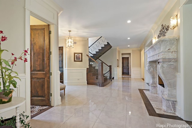 foyer featuring a decorative wall, an inviting chandelier, a fireplace, recessed lighting, and stairs