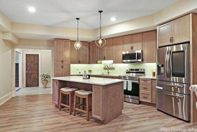 kitchen with a sink, light countertops, light wood-style floors, and stainless steel appliances