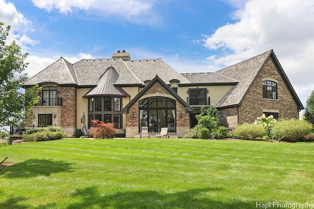 view of front of house with brick siding, a front lawn, stucco siding, and a chimney