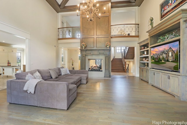living room featuring a wealth of natural light, stairway, a chandelier, and light wood finished floors