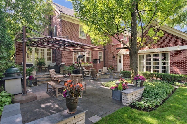 rear view of property with a patio area, a fire pit, and brick siding