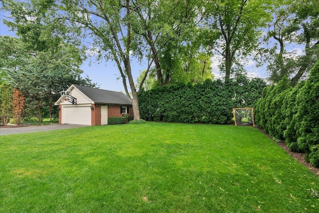 view of yard featuring an outdoor structure, a garage, and aphalt driveway