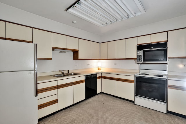 kitchen with light countertops, a sink, black appliances, and white cabinetry