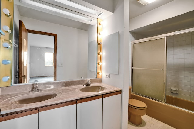 full bathroom featuring a sink, toilet, double vanity, and enclosed tub / shower combo