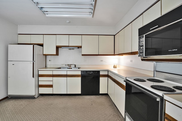 kitchen with black dishwasher, a sink, light countertops, freestanding refrigerator, and electric stove