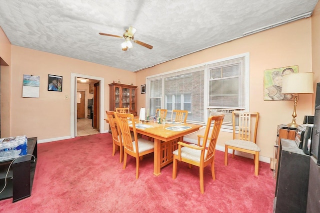 dining area with a textured ceiling, ceiling fan, light colored carpet, and baseboards