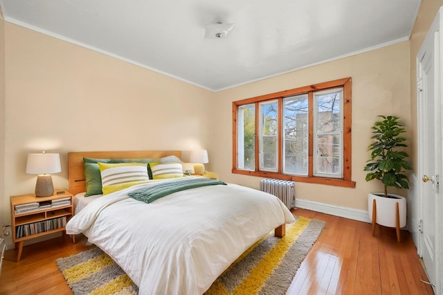bedroom featuring crown molding, radiator heating unit, wood-type flooring, and baseboards