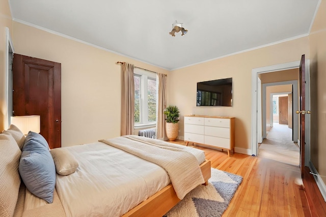 bedroom with light wood-type flooring, radiator, crown molding, and baseboards