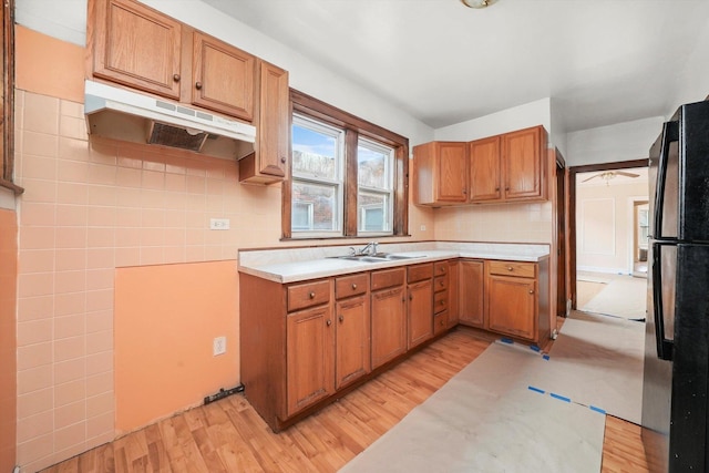kitchen with a sink, freestanding refrigerator, light wood-style floors, and under cabinet range hood