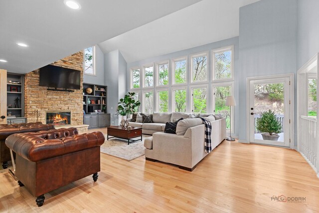 living room with visible vents, wood finished floors, a stone fireplace, high vaulted ceiling, and recessed lighting