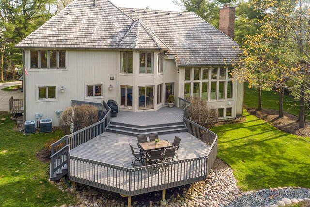 back of house with a lawn, a wooden deck, a chimney, and outdoor dining space