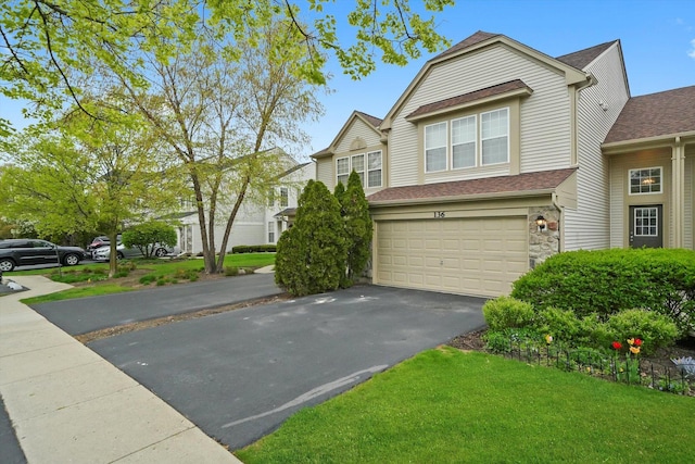 view of front of house with an attached garage, asphalt driveway, and a shingled roof