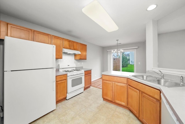 kitchen with white appliances, under cabinet range hood, a sink, a chandelier, and light countertops