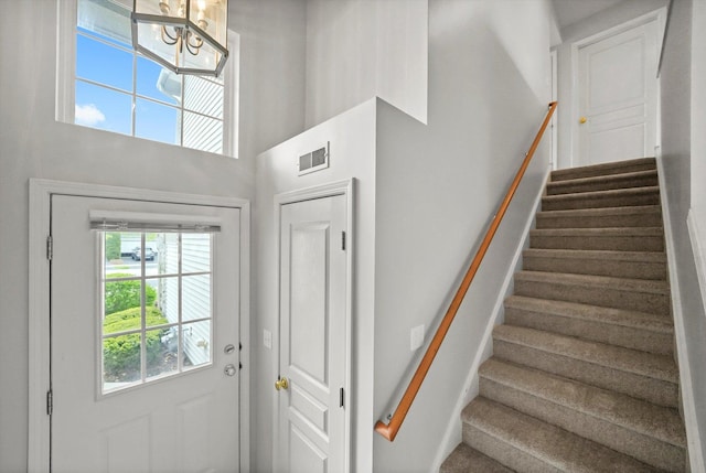 stairs featuring a chandelier and a towering ceiling
