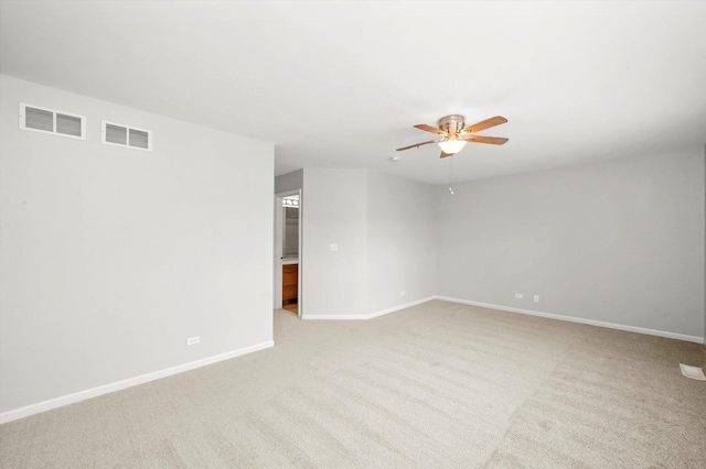 spare room featuring ceiling fan, light carpet, and baseboards