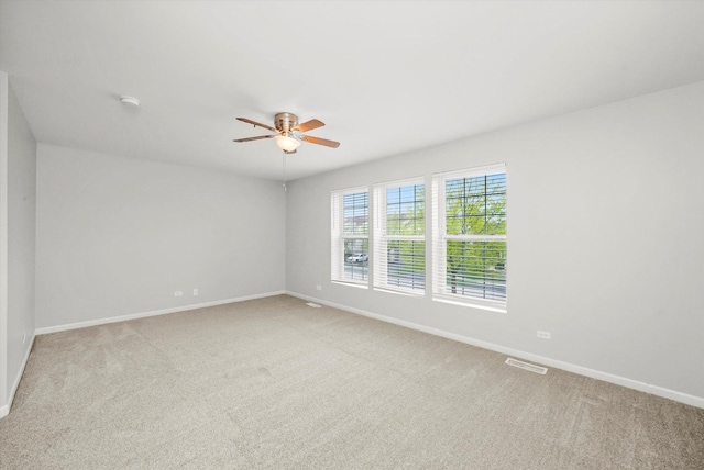 empty room with a ceiling fan, baseboards, and light carpet